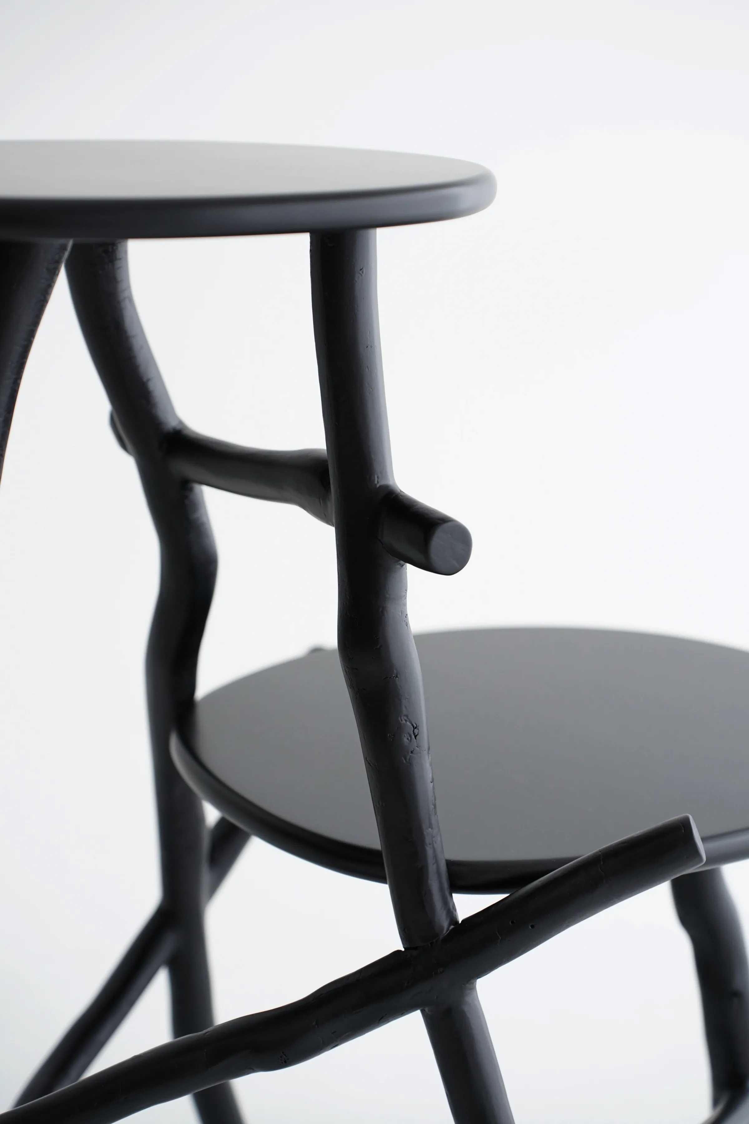 Uneri pair of stools detail showing branch leg structure and circular linden plywood tops in matte black enamel